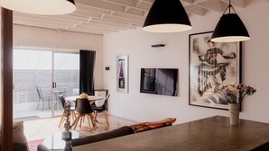A modern living room with a dining area, featuring a large window, a dining table with chairs, and a coffee table. - Urban Warehouse Retreat in West Hobart (West Hobart)
