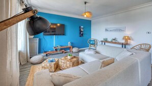 A living room with a blue accent wall, a sofa, a television, and a wicker chair.