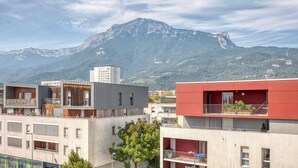 A modern building with balconies and a mountain in the background.