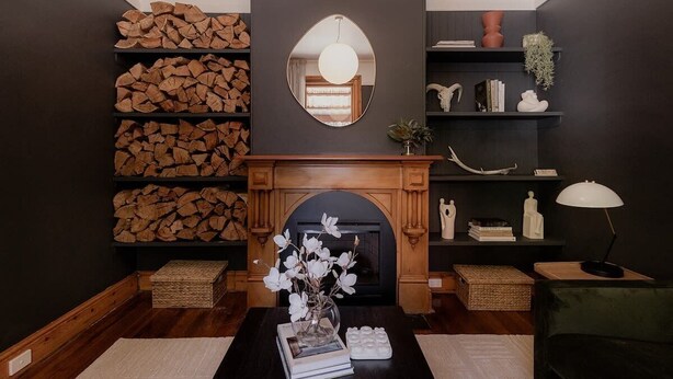 Un salon chaleureux avec une cheminée, des étagères à livres et un miroir au-dessus du manteau de cheminée.