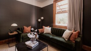 Un salon moderne avec un mur de couleur sombre, un canapé vert, une table basse et un lampadaire.