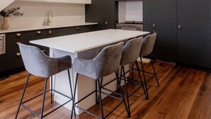 Une cuisine moderne dotée d’un îlot central, de meubles de couleur sombre et d’un escalier en bois.