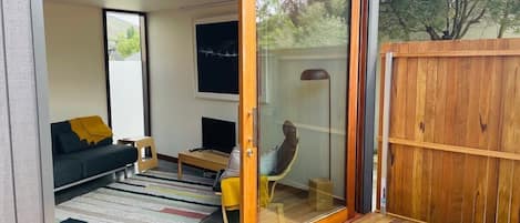 A modern living room with a sofa, a chair, a TV, and a wooden deck.