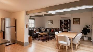 A modern living space with a kitchen, dining area, and a sofa set.