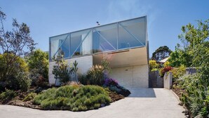 A modern house with a glass facade, surrounded by landscaped gardens and a clear sky. - Architectural Glass House with Breathtaking Ocean Views (Taroona)