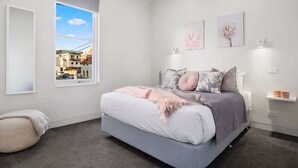Une chambre à coucher avec un grand lit, une fenêtre et des œuvres d’art accrochées au mur.