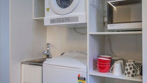 Un espace buanderie équipé d’un lave-linge, d’un sèche-linge et d’un four à micro-ondes.