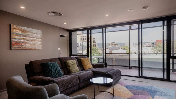 A modern living room with a sofa, armchair, and a coffee table. - Fantastic CBD Apartment with Views (Hobart)