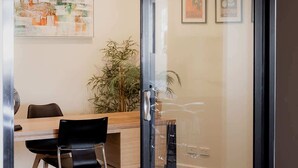 A modern conference room with a glass door, a wooden table, black chairs, and a potted plant. - Fantastic CBD Apartment with Views (Hobart)