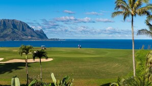 A golf course with a clear view of the ocean and mountains in the background.