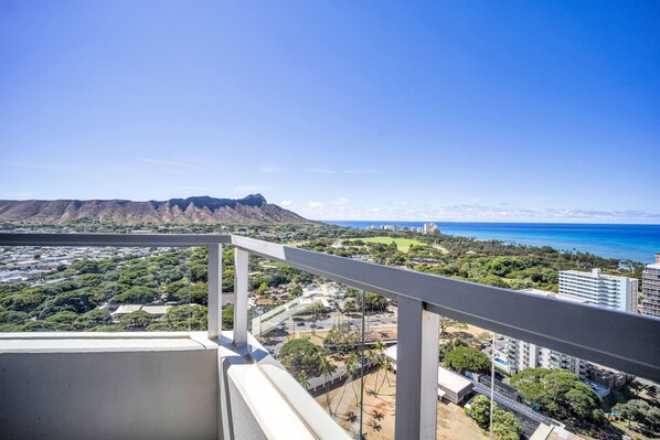 A balcony with a view of a coastal cityscape, including buildings and a mountain. - Stunning Ocean & Diamond Head Views Await at 2Bedroom Diamond Head Vista (Honolulu)