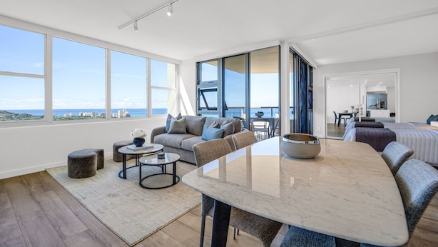 A spacious living area with a large window, a dining table, and a sofa.
