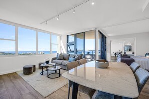 A spacious living area with a large window, a dining table, and a sofa.