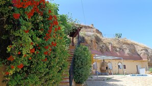 Un edificio de piedra con un patio, una pequeña piscina y una escalera que lleva a una zona cubierta.