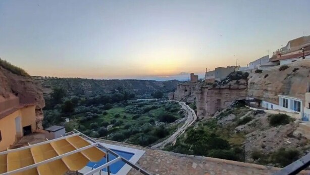 Vista de un valle con un río, edificios en la ladera y una zona de piscina.