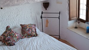 Un dormitorio con cama, ventana y un estante en la pared.