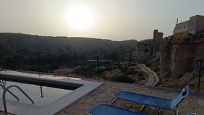 Zona de piscina con sillas de descanso y vistas a un paisaje montañoso.