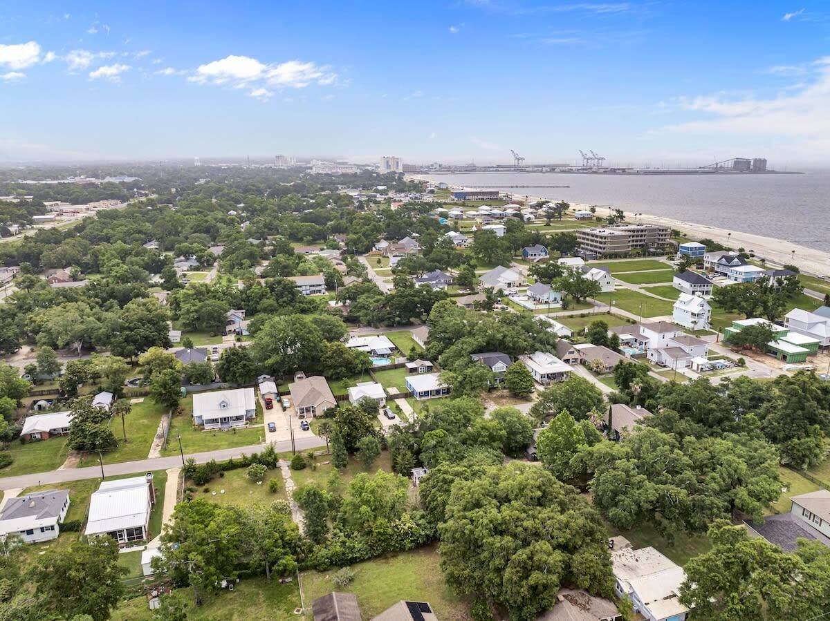Vista aérea de una zona residencial con casas, áreas verdes y una orilla de agua.