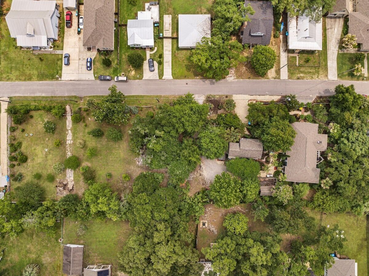 An aerial view of a residential area with houses, roads, and greenery.