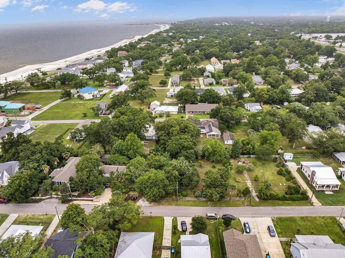 An aerial view of a residential area with houses, roads, and a beach in the background.