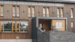 A spa hotel with a wooden facade, a stone entrance, and a sign indicating the name and years 2023-2024. - 4 Star Holiday Home in Hisings Backa (Hisings Backa)