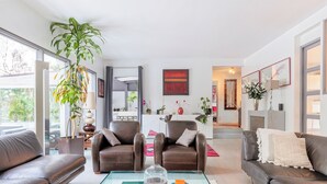 A modern living room with leather sofas, a glass coffee table with books, and a large plant.