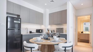 A modern kitchen with a built-in refrigerator, microwave, and stove. There is a dining table with chairs and a small island with a sink.