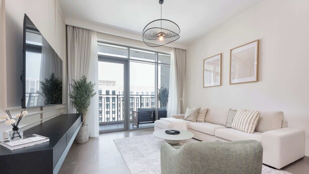 A modern living room with a sofa, a coffee table, a TV, and a balcony with a view.