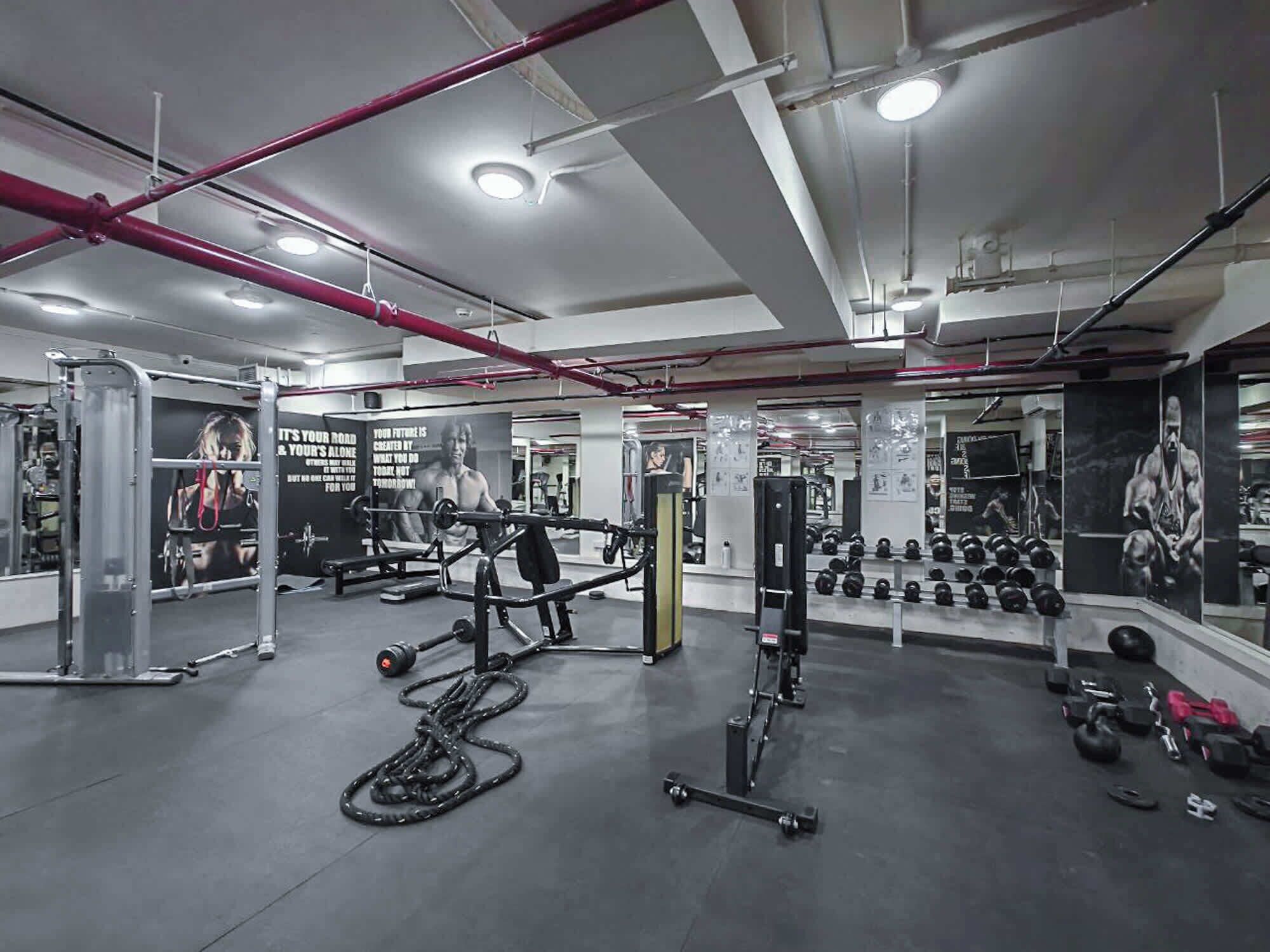 A gym with various exercise equipment, mirrors, and motivational posters.