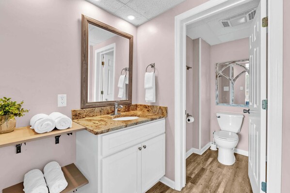 Ein Badezimmer mit Waschbecken, Spiegel, Handtuchhalter und Toilette.