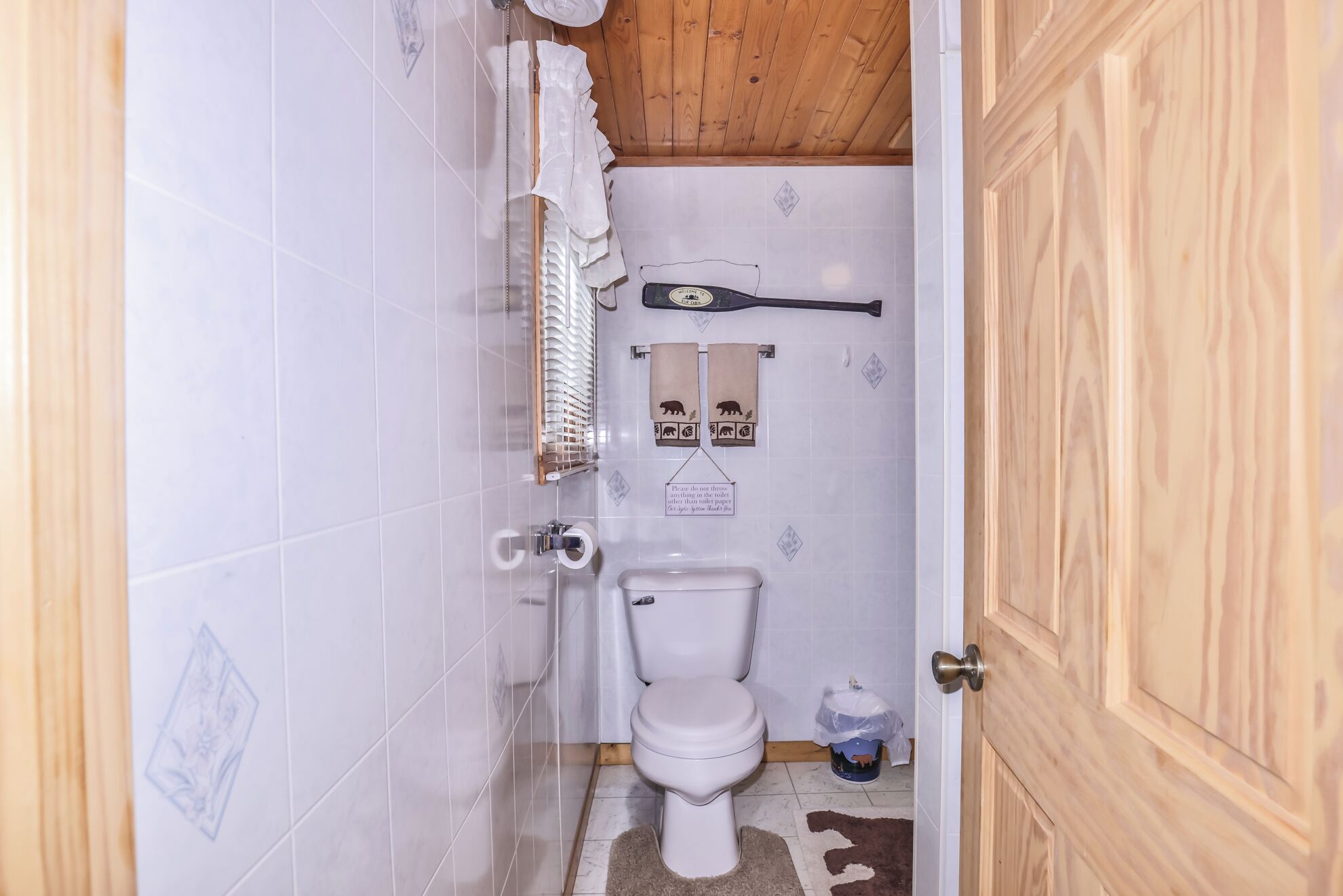 Un baño pequeño y funcional con inodoro, zona de ducha y techo de madera.