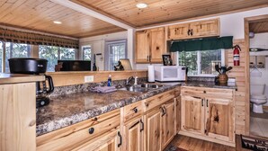 A kitchen with wooden cabinets, granite countertops, a microwave, and a coffee maker. - Stepaway Vacation Rentals-Cozy Cottage (St.Germain)