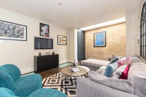 Relax in a stylish living room with a large flat-screen TV, comfortable seating area, and geometric patterned rug.