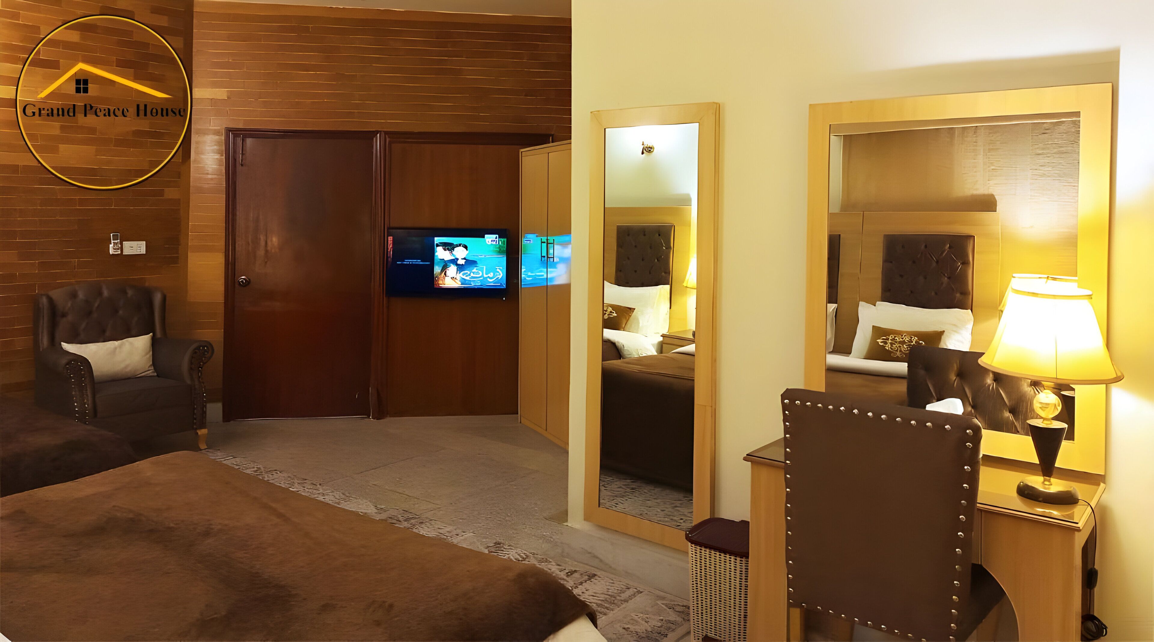 A hotel room with a television, a bed, a chair, a mirror, and a lamp.