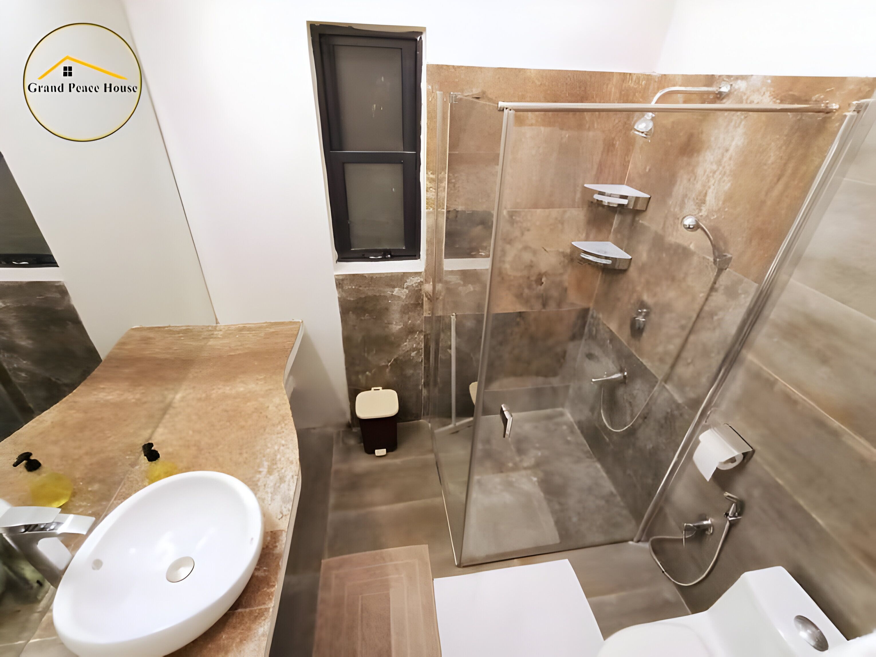 A modern bathroom with a glass-enclosed shower, a white sink, and a toilet.