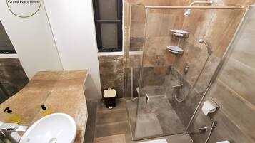 Un baño moderno con ducha de vidrio, lavamanos blanco y retrete.