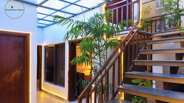 Un interior moderno con una escalera, puertas de madera y plantas en macetas.