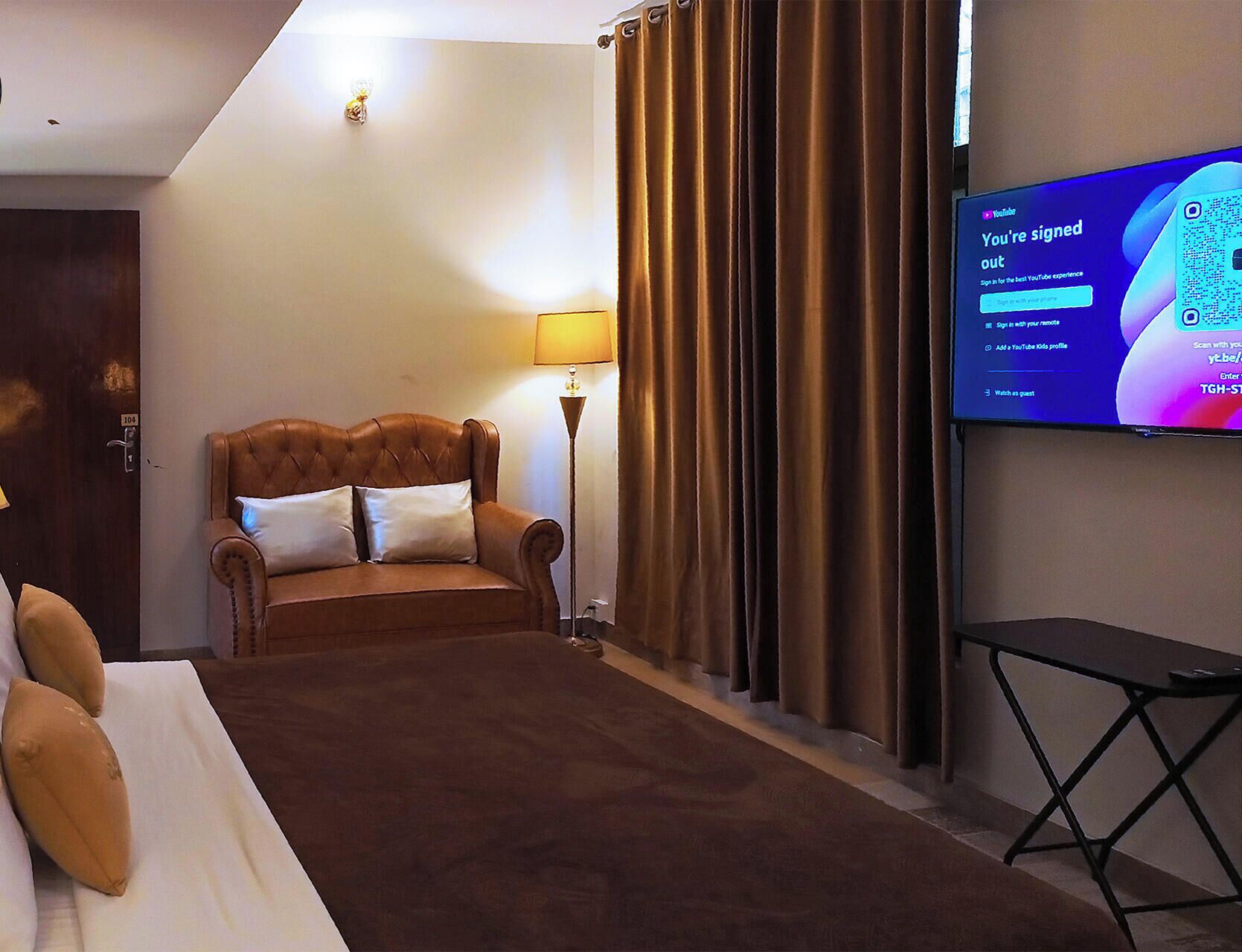 A hotel room with a bed, a TV, a lamp, and curtains.