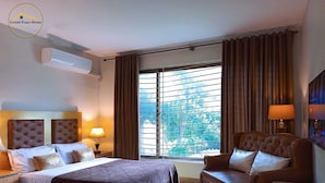 A hotel room with two beds, a sofa, a TV, and a window with curtains. - Grand Peace House II (Islamabad)