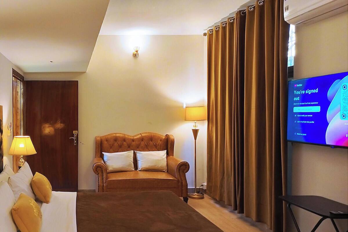 A hotel room with a bed, a sofa, a TV, and a lamp.