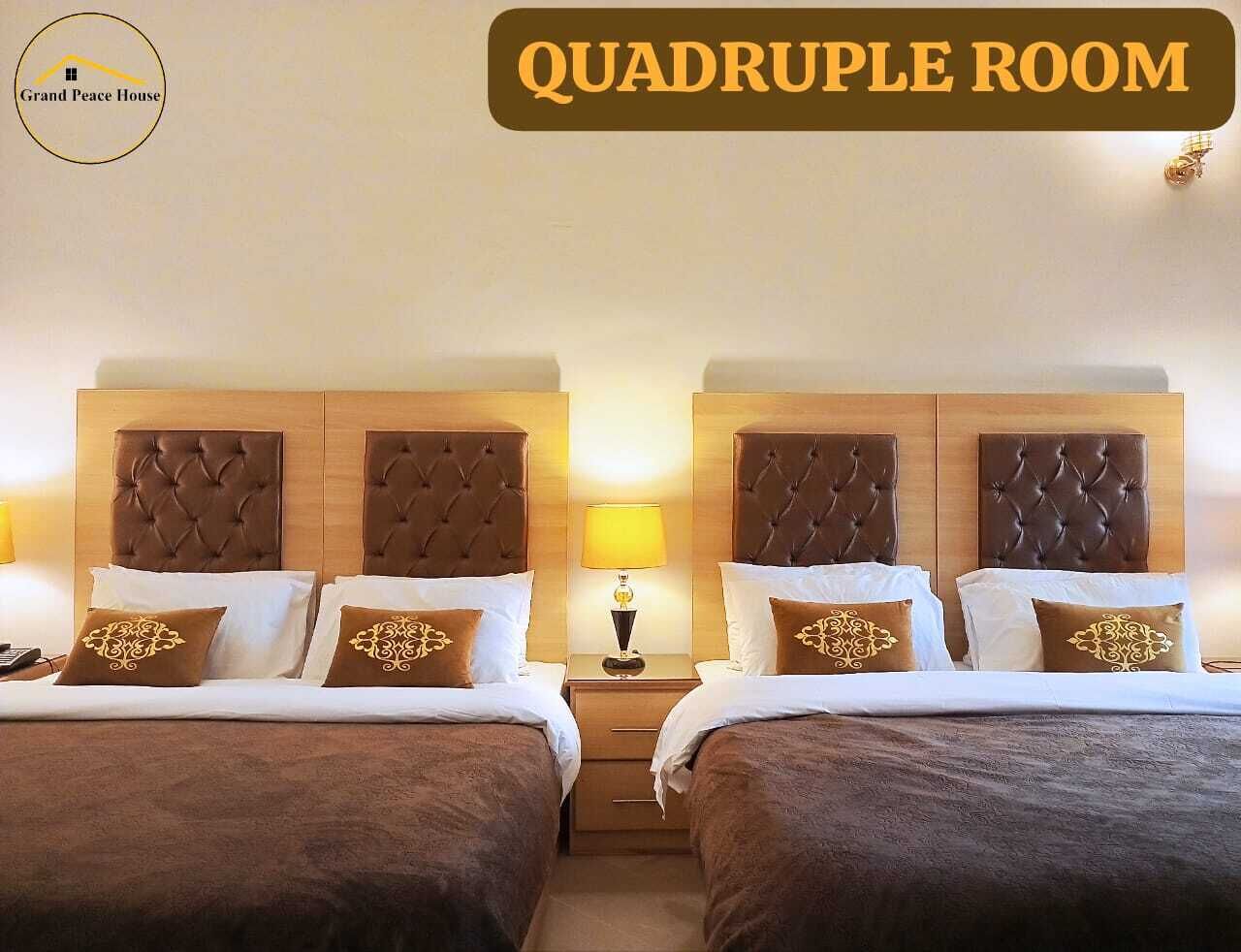 Cuádruple habitación con dos camas, cada una con cabecero capitonado, mesitas de noche, lámparas y almohadas decorativas.