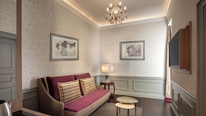 A room with a sofa, two side tables, a chandelier, and framed artwork on the walls. - The Inn at the Spanish Steps Elegant Collection - The Jewel (Rome)
