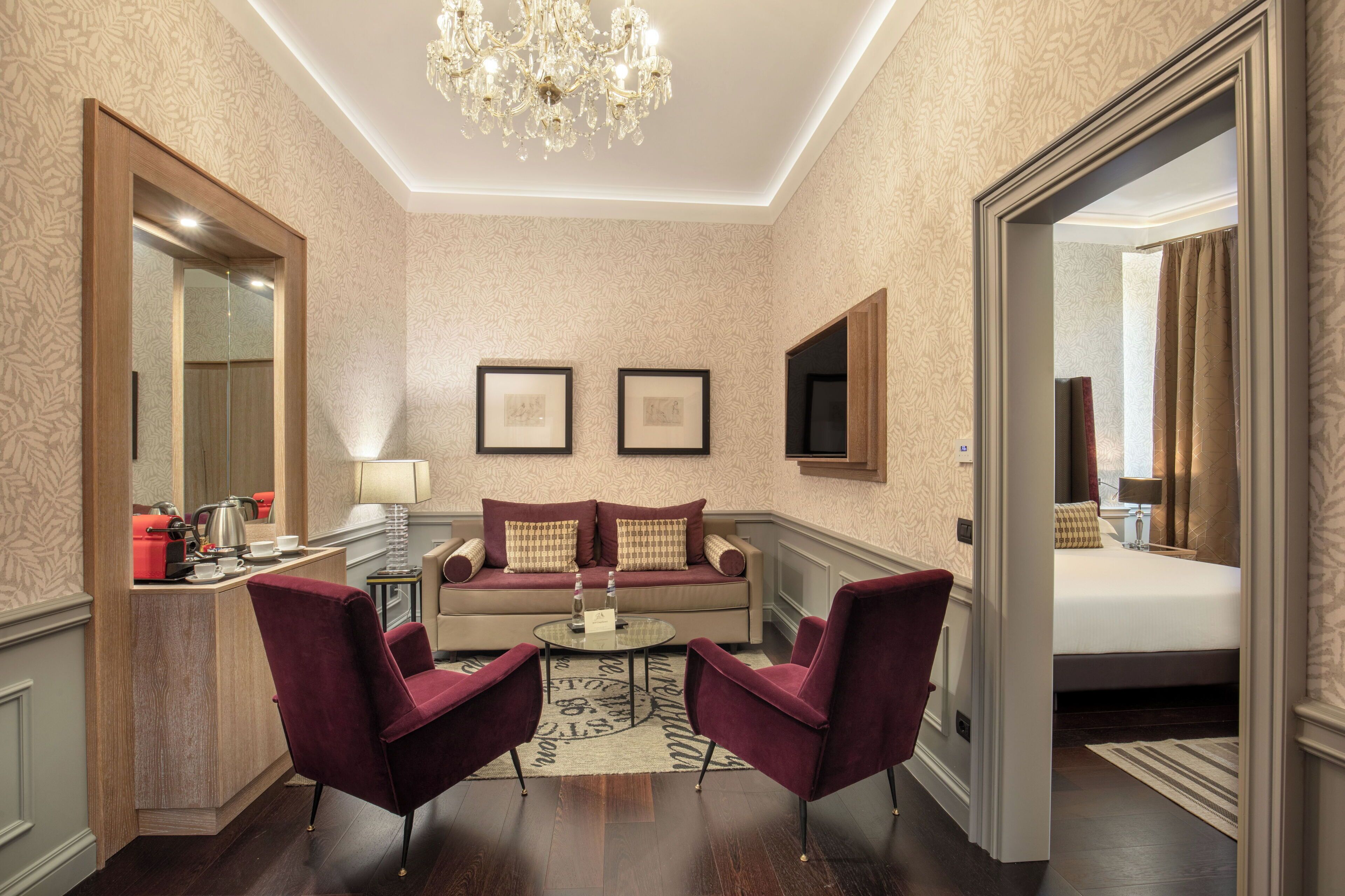 Une chambre d’hôtel avec un canapé, deux fauteuils, une table basse, une télévision et un lit.