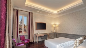 A hotel room with a bed, desk, two chairs, a TV, and a window with a view of a building. - The Inn at the Spanish Steps Elegant Collection - The Jewel (Rome)