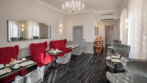 A dining area with red and grey upholstered seating, black marble flooring, and a chandelier. - The Inn at the Spanish Steps Elegant Collection - The Jewel (Rome)