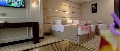Una habitación de hotel con cama, mesitas de noche, televisión y una lámpara decorativa.