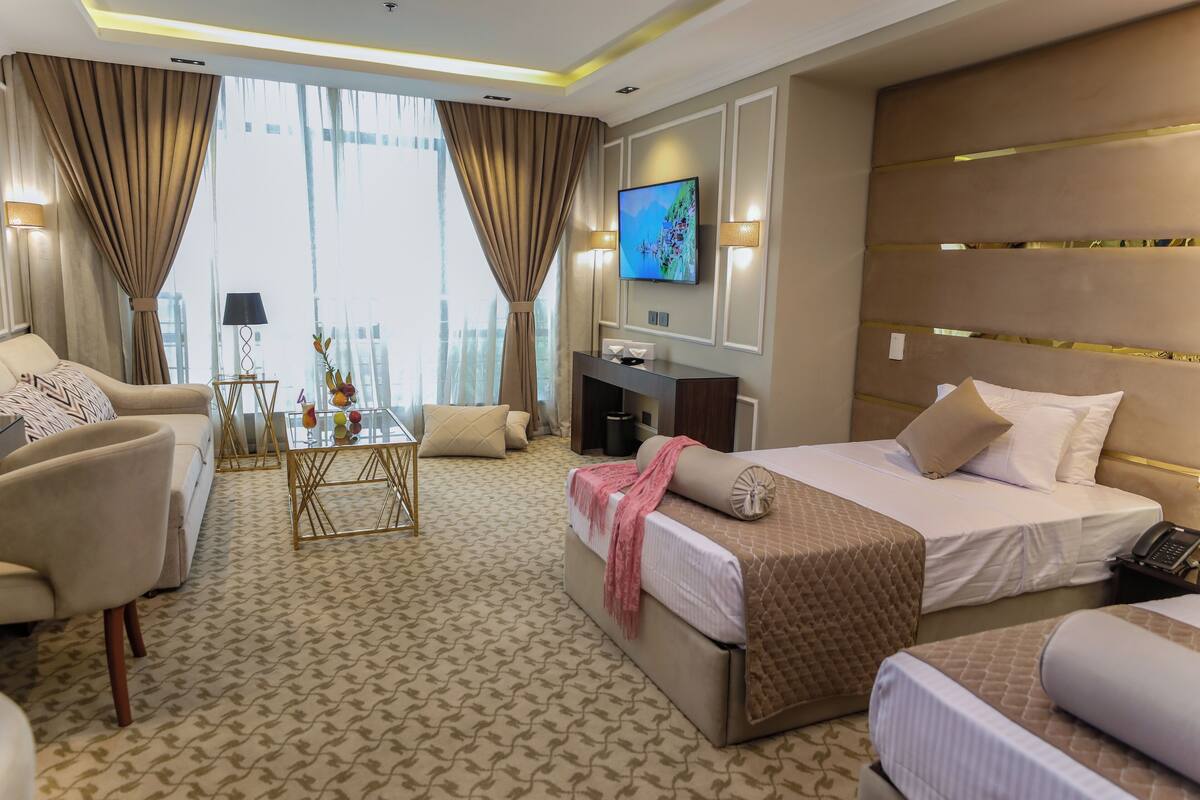 Una camera d'albergo con un letto grande, un divano, un tavolino da caffè e una TV a parete.