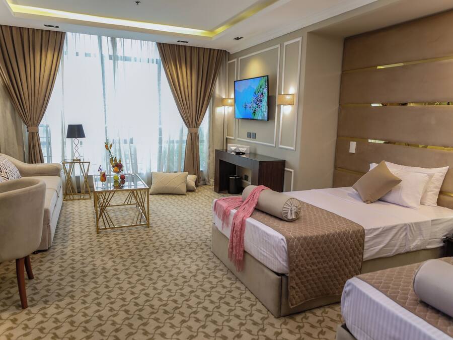 Ein Hotelzimmer mit einem großen Bett, einer Couch, einem Couchtisch und einem an der Wand befestigten Fernseher.