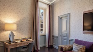 Une chambre d’hôtel équipée d’un bureau, d’une chaise et d’un canapé agrémenté de coussins décoratifs.