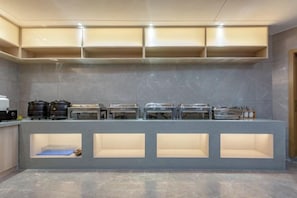 A buffet setup with multiple food stations, a counter with a sink, and a tiled floor. - GYA Hotel (Jiaxing Nanhu Scenic Area Nanhu Tiandi) (Jiaxing)